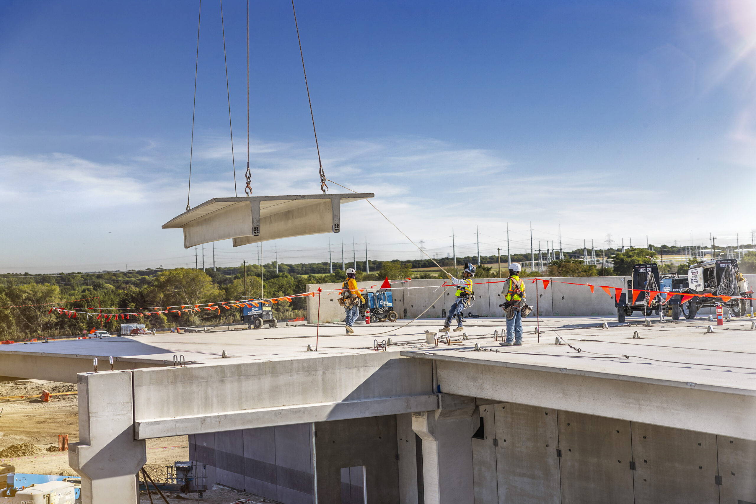 Workers guiding a precast concrete section into place during data center construction.