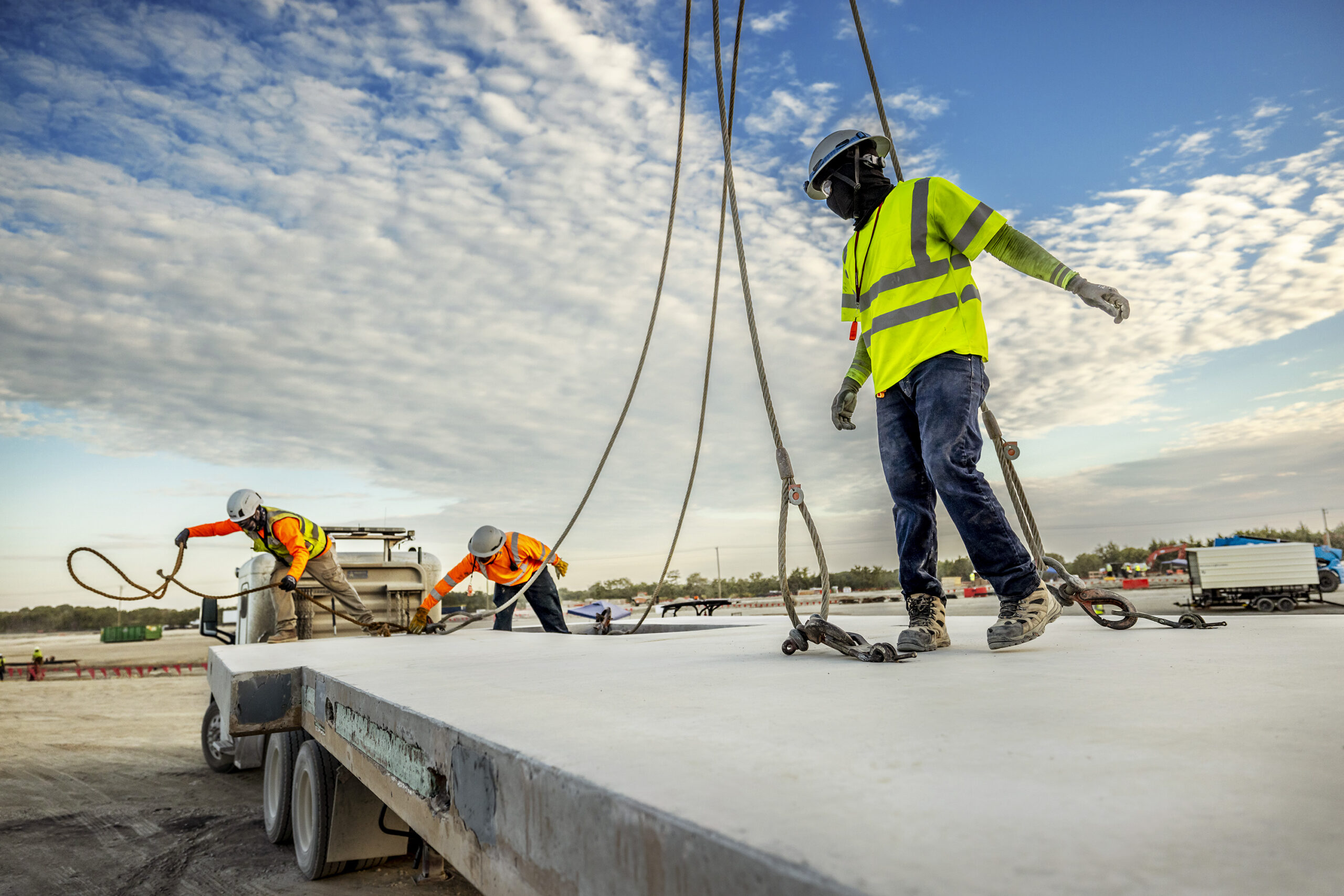 Workers installing a precast concrete panel during data center construction.