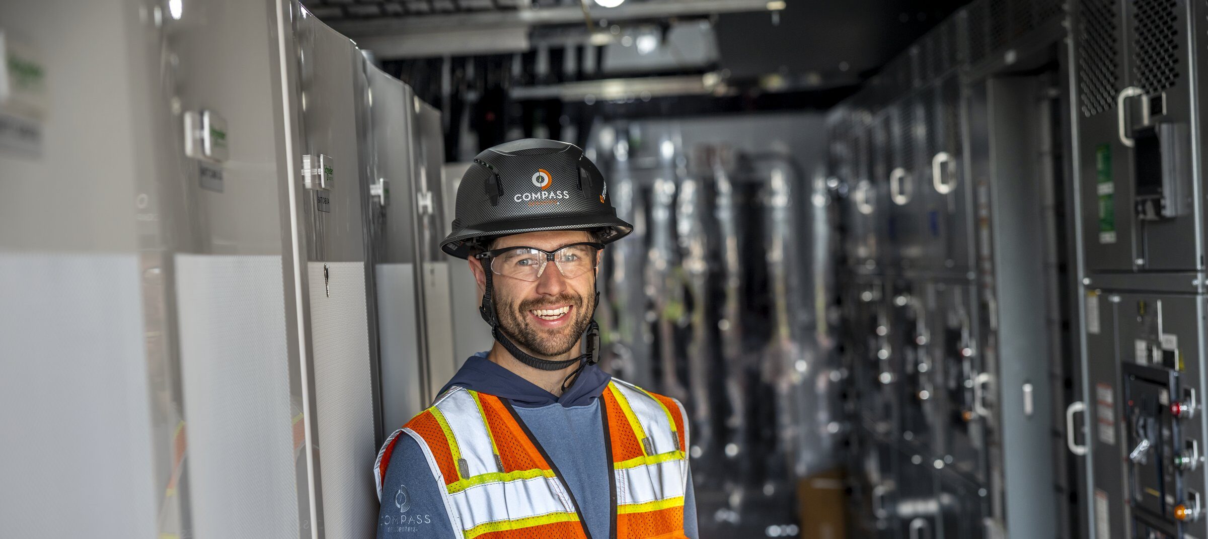 Un tecnico di impianto di un data center, equipaggiato con dispositivi di sicurezza, lavora all’interno di un ambiente infrastrutturale critico che supporta operazioni digitali e sistemi elettrici.